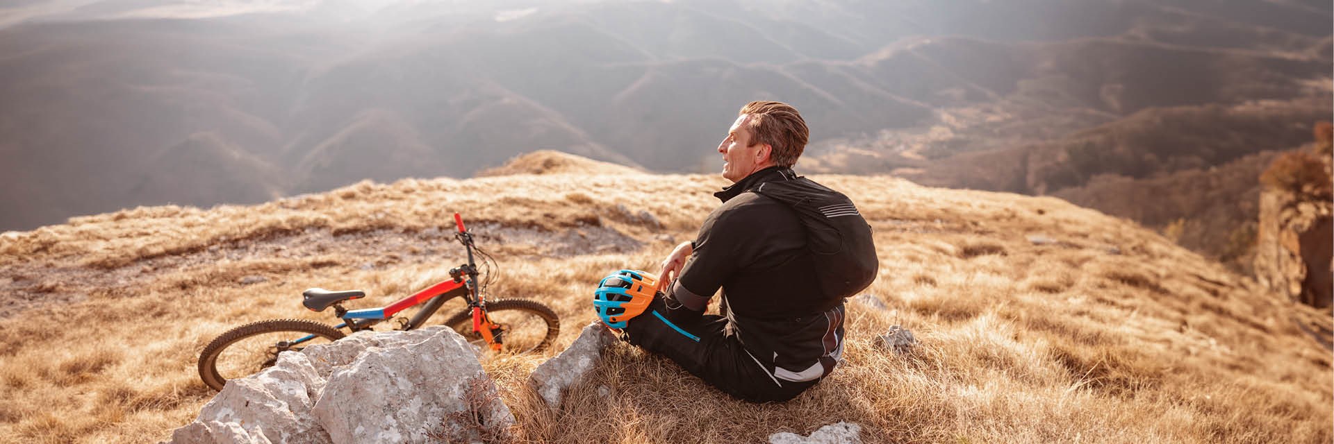 Man sitting on a hillside with his mountain bike