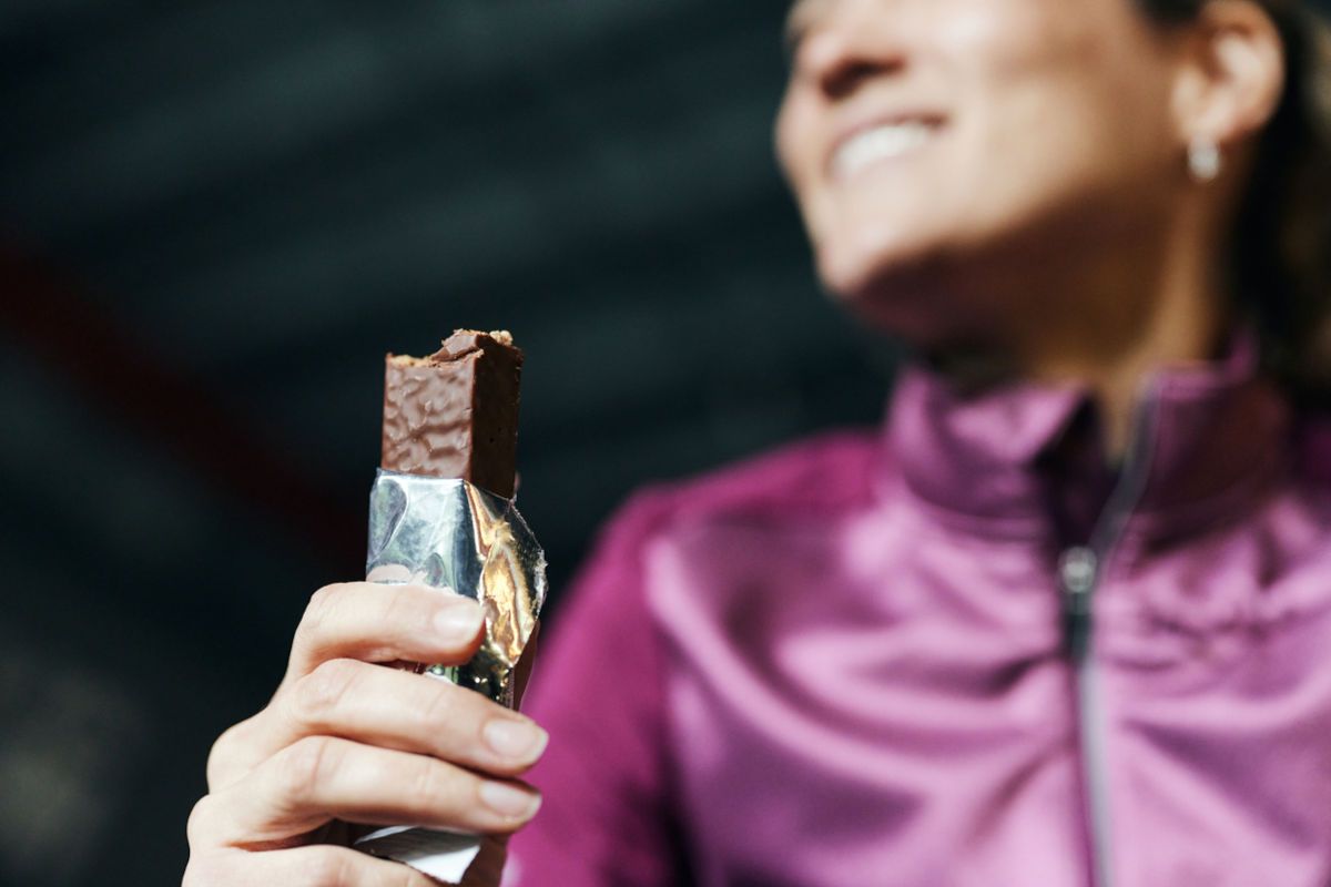 Female athlete holding unwrapped protein bar