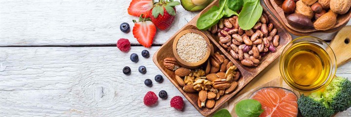 Overhead shot of fruit, nuts, salmon and avocado on a white wooden background