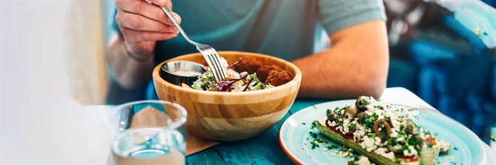 Man eating salad from wooden bowl
