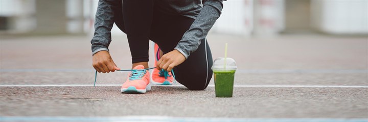 Athlete tying shoelace with greens drink