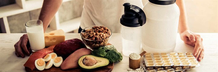 Man with healthy snacks and protein shakes in kitchen
