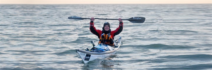 Sarah Outen in a kayak holding up her oar