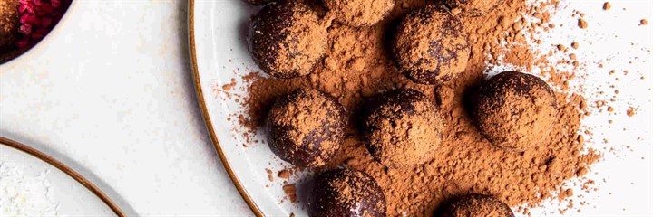 Fruit and nut energy balls on a plate with cocoa powder dusted on top
