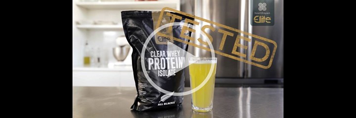 Healthspan Elite All Blacks Clear Whey Isolate packaging and glass of orange protein drink on kitchen counter