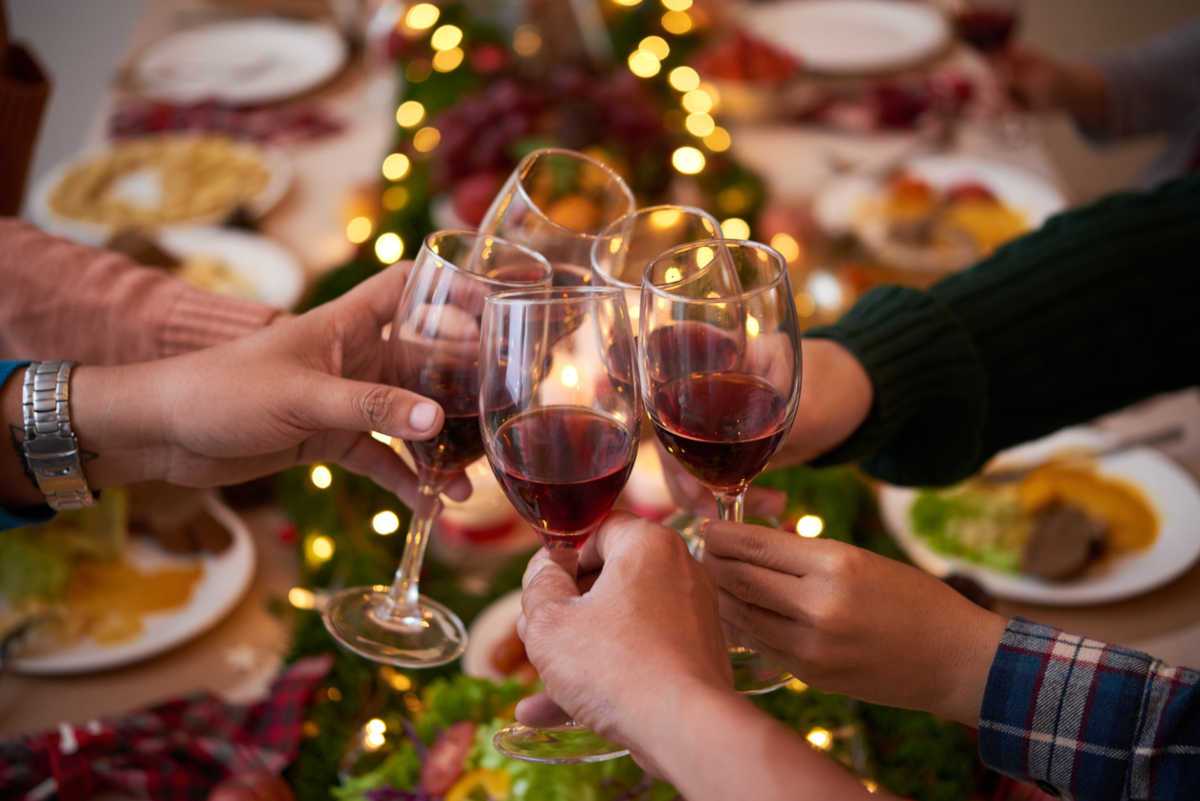People clinking wine glasses over Christmas dinner