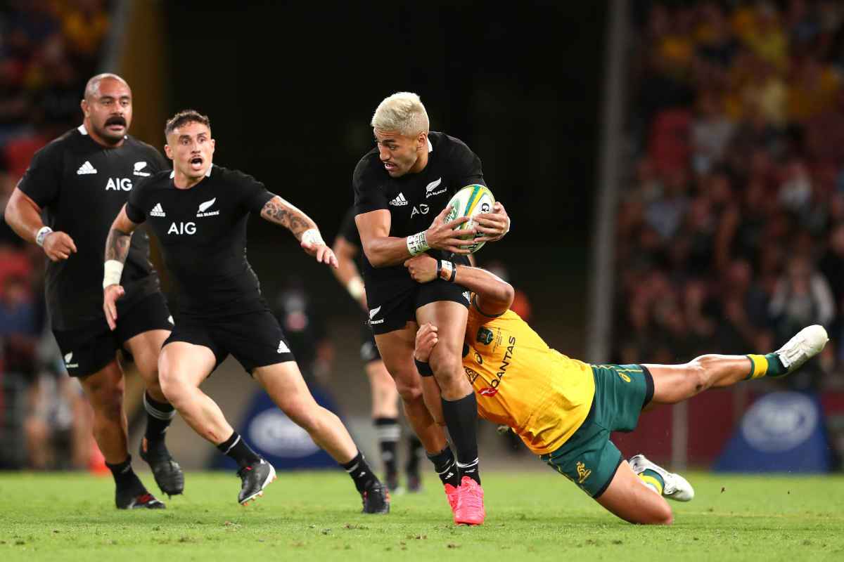 Three New Zealand All Blacks' players running with rugby ball against Wallabies rugby team